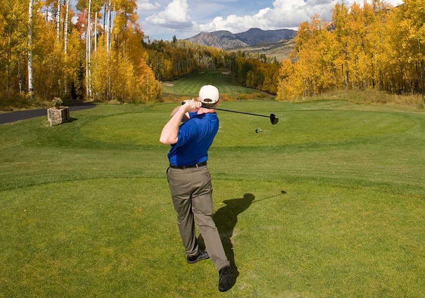Golfer Teeing Off in Fall with Mountains in Distance | Glenwood Hot Springs Resort