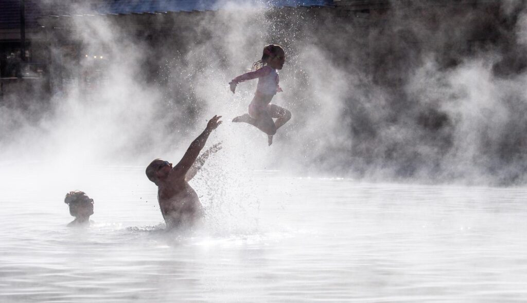 Father tossing daughter in the steam-filled air at the Grand Pool at Glenwood Hot Springs Resort