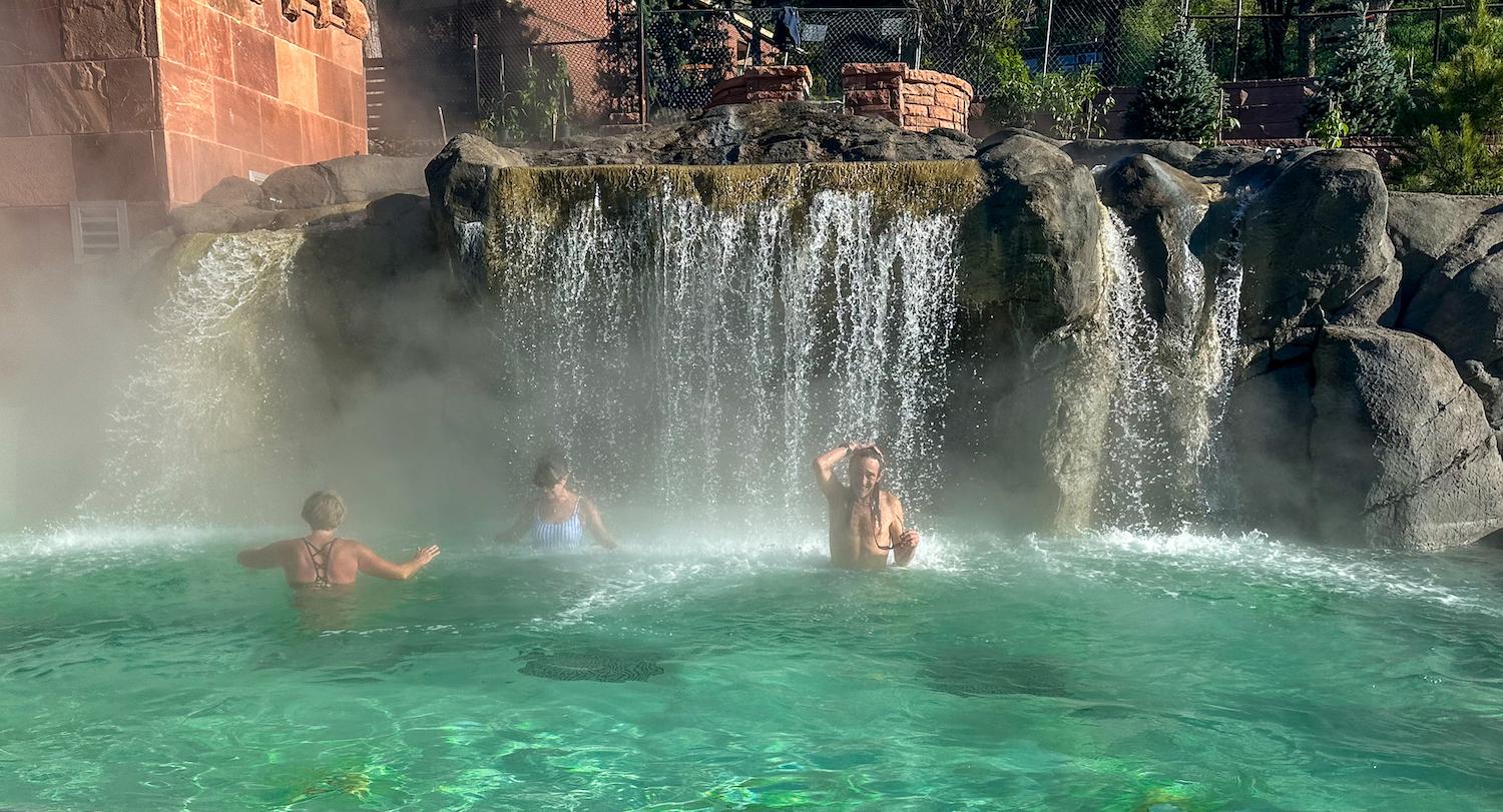 Guests enjoying the Falling Waters waterfall in Yampah Mineral Baths at Glenwood Hot Springs Resort