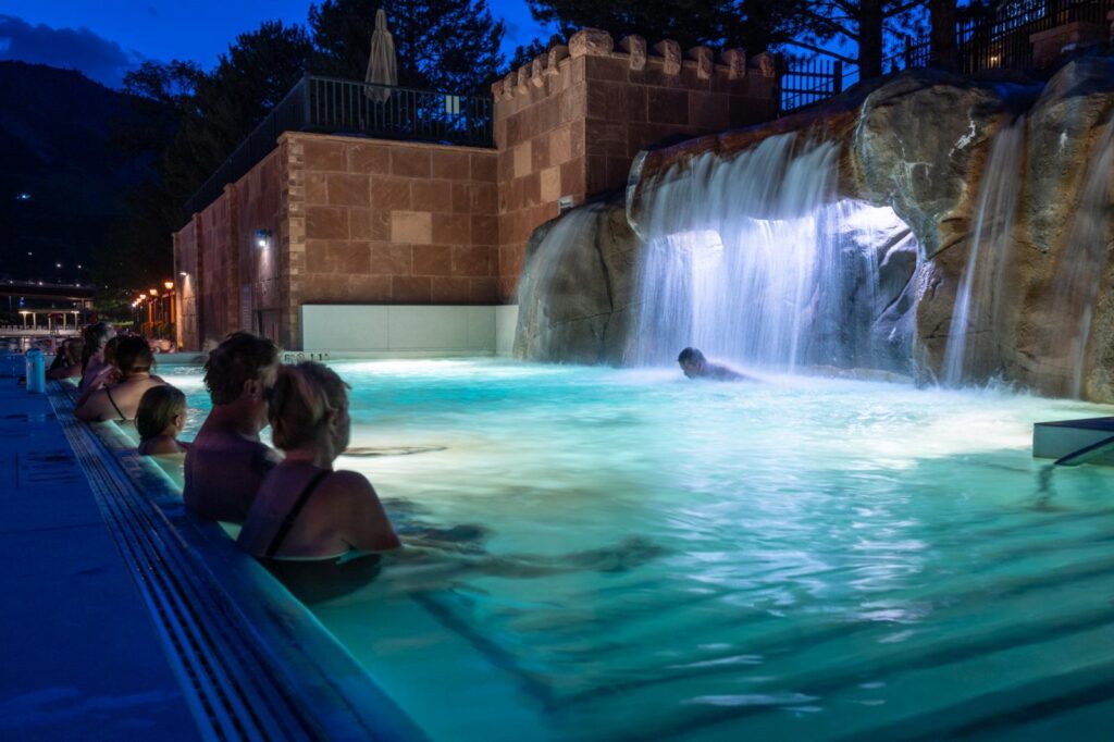 Guests enjoying the Falling Waters Pool and waterfall in the Yampah Mineral Baths at Glenwood Hot Springs Resort