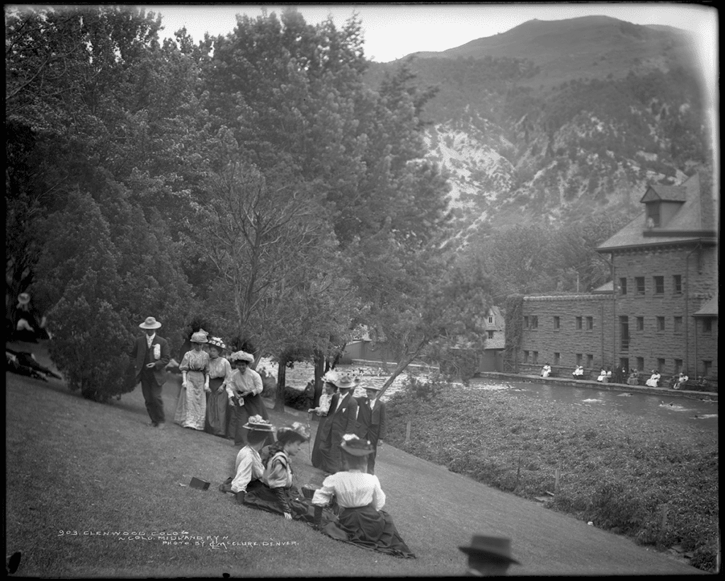 Picnickers on hill behind Grand Pool and historic Stone Bath House at Glenwood Hot Springs Resort