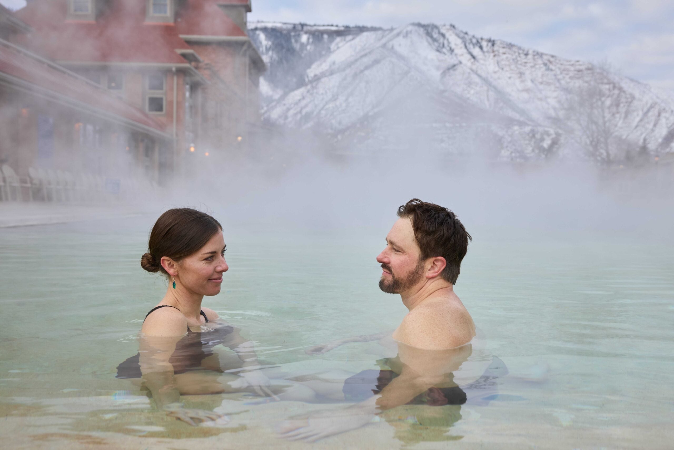 Couple standing in Grand Pool in the winter at Glenwood Hot Springs Resort