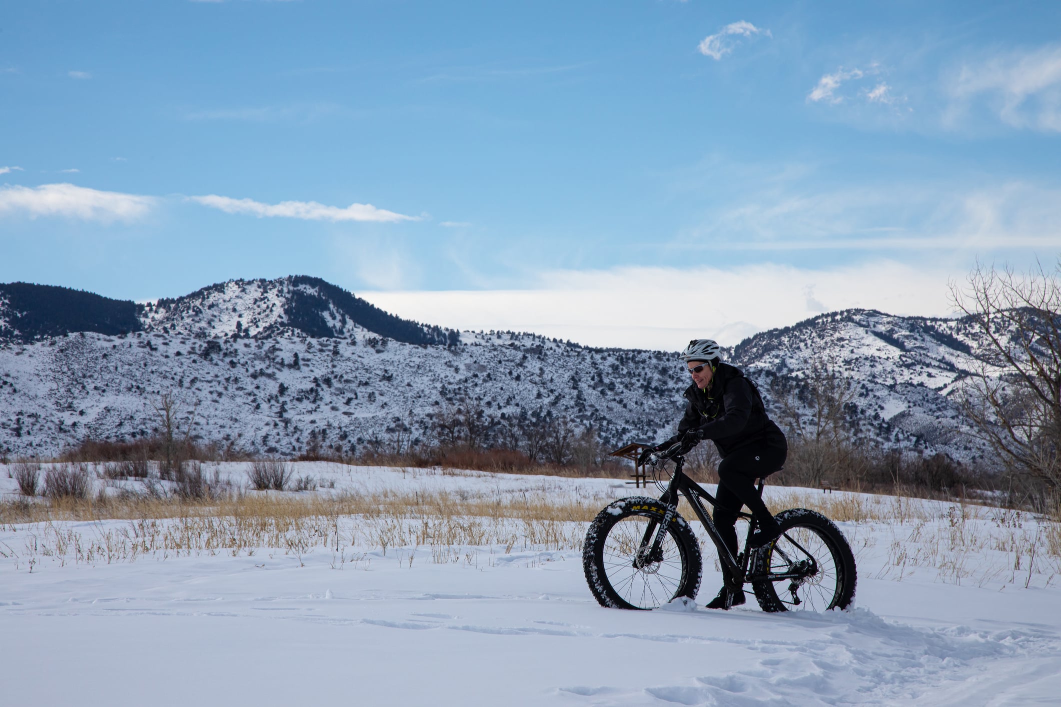 Female fat tire mountain bike rider pedaling across snow covered field near Glenwood Hot Springs Resort